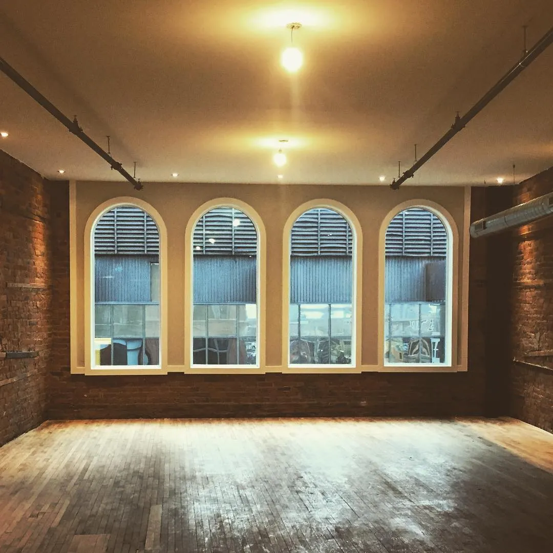 Commercial space with arched window trim and exposed brick by Walkercraft Carpentry