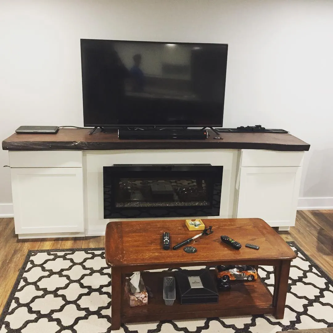 Custom built-in fireplace unit with white cabinets and live-edge mantel by Walkercraft Carpentry