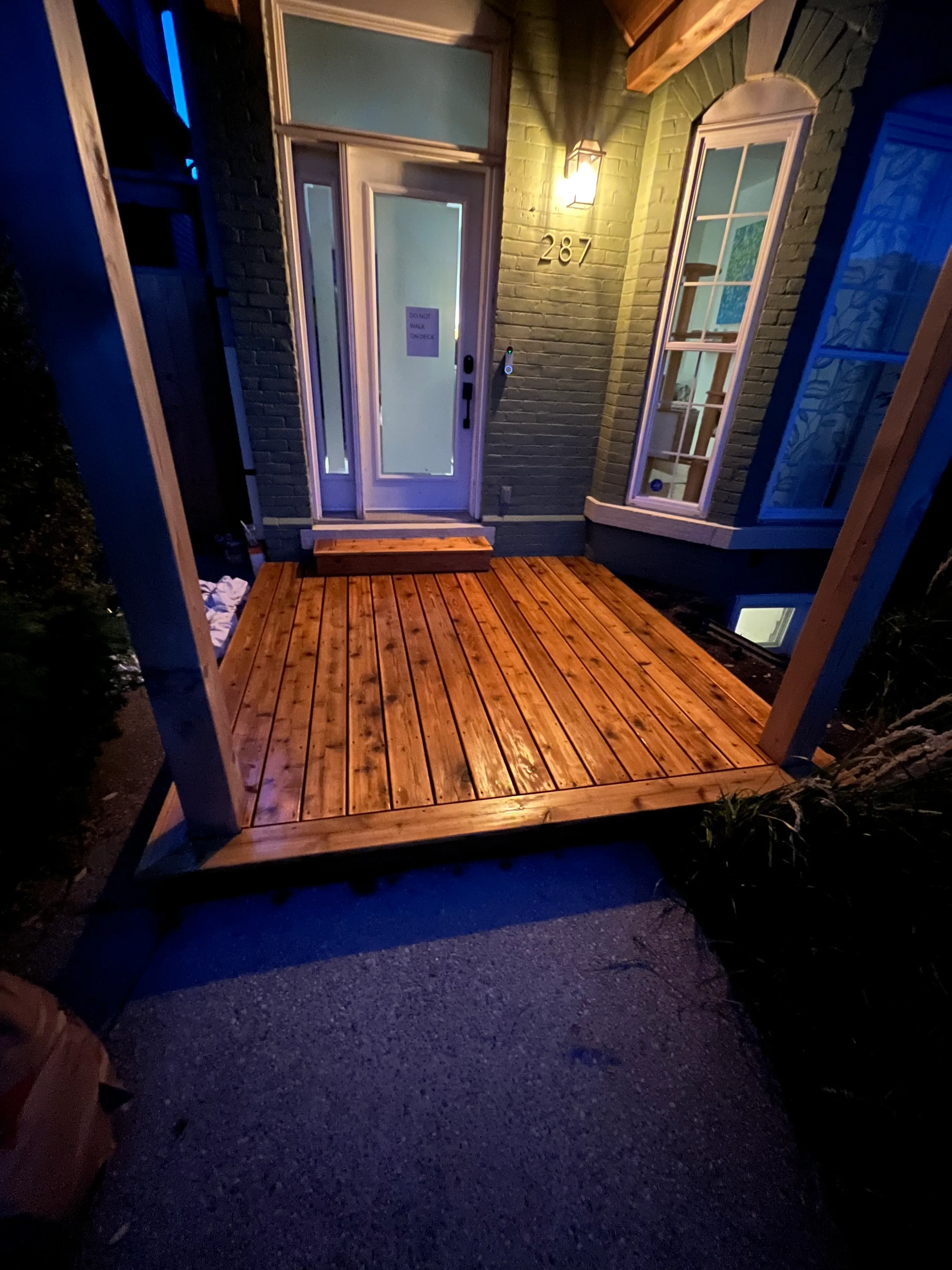 Cedar front porch deck illuminated at night by Walkercraft Carpentry
