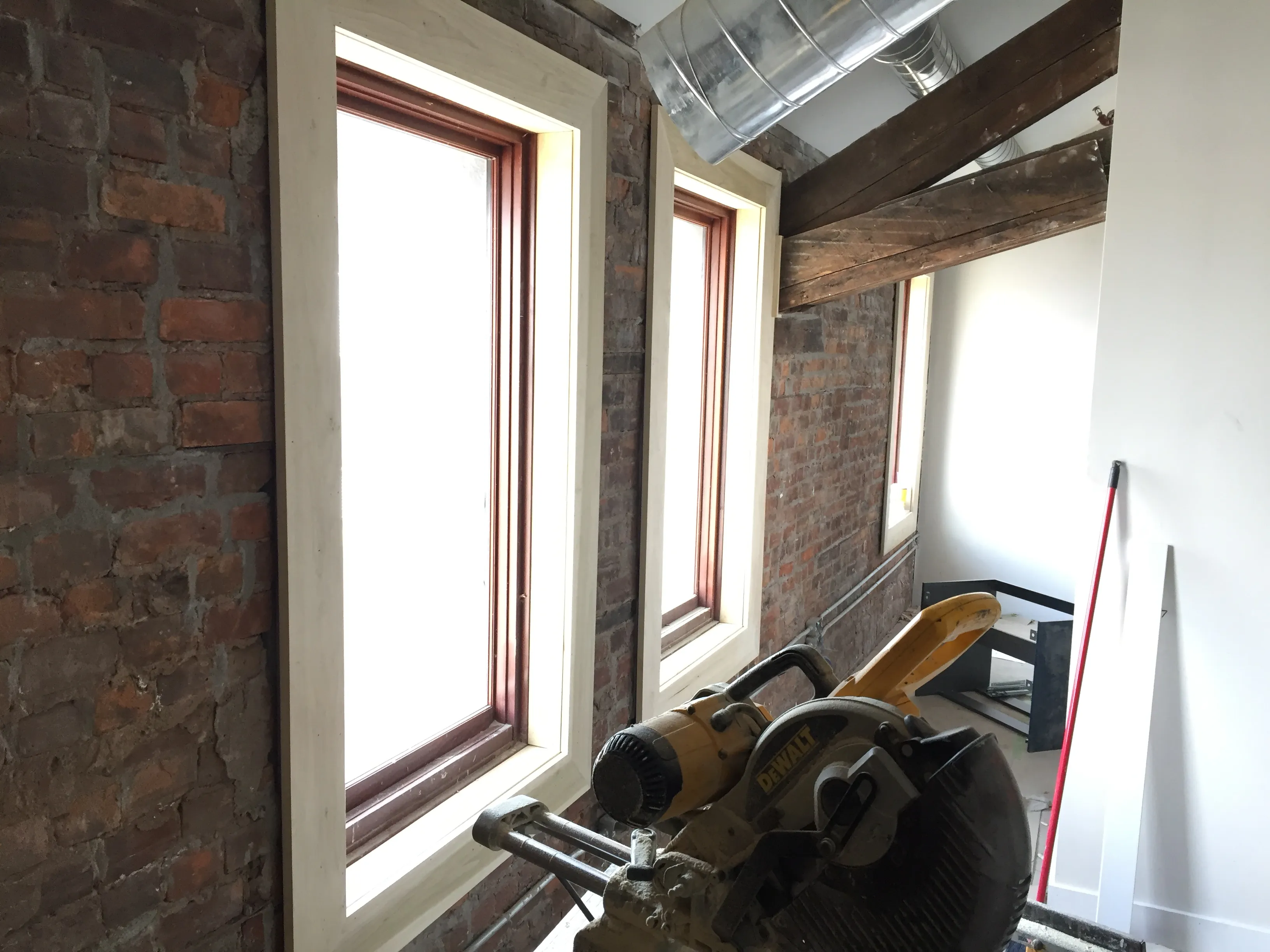 Custom window trim with exposed brick and timber beams by Walkercraft Carpentry